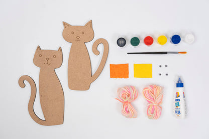 Cat Yarn Craft Kit contents with two MDF cat cut-outs, acrylic paint pots, paint brush, colourful yarn, glue, felt pieces and googly eyes arranged on a white background.