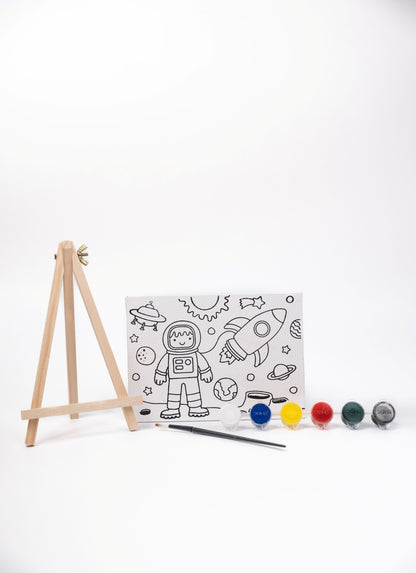Space Canvas Painting Kit contents featuring a pre-printed space canvas, wooden easel, six acrylic paint pots and paint brush on a white background.