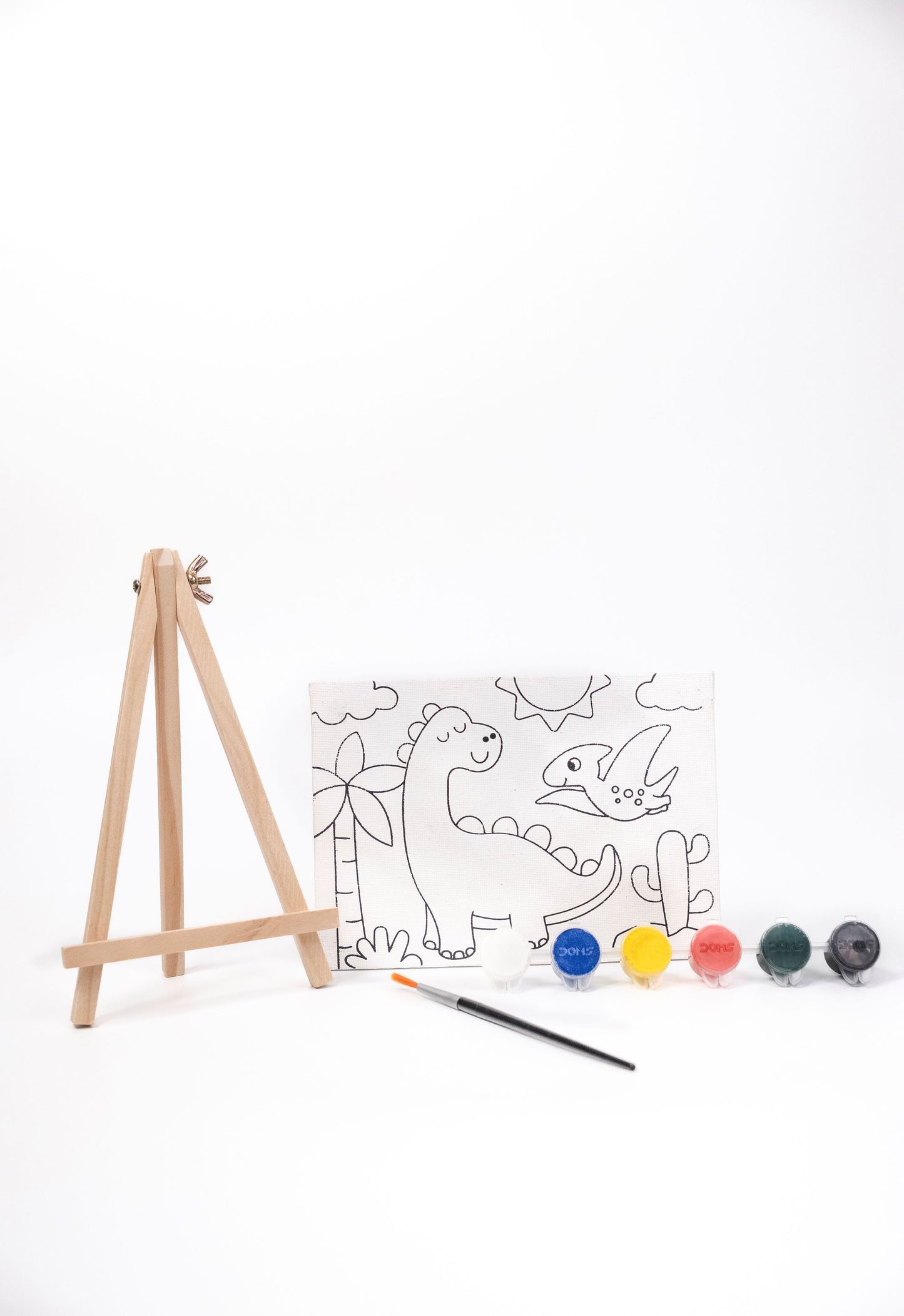Dinosaur Canvas Painting Kit contents featuring a pre-printed dinosaur canvas, wooden easel, six acrylic paint pots and paint brush on a white background.