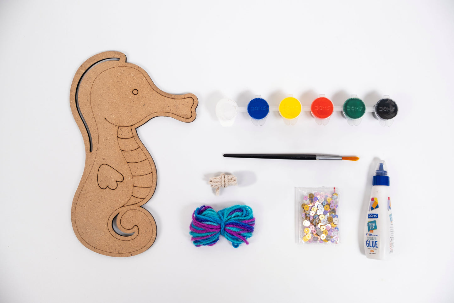 Creative Craft Kit – Seahorse contents with MDF seahorse, acrylic paints, brush, glue, yarn, sequins and hanging thread on white background.
