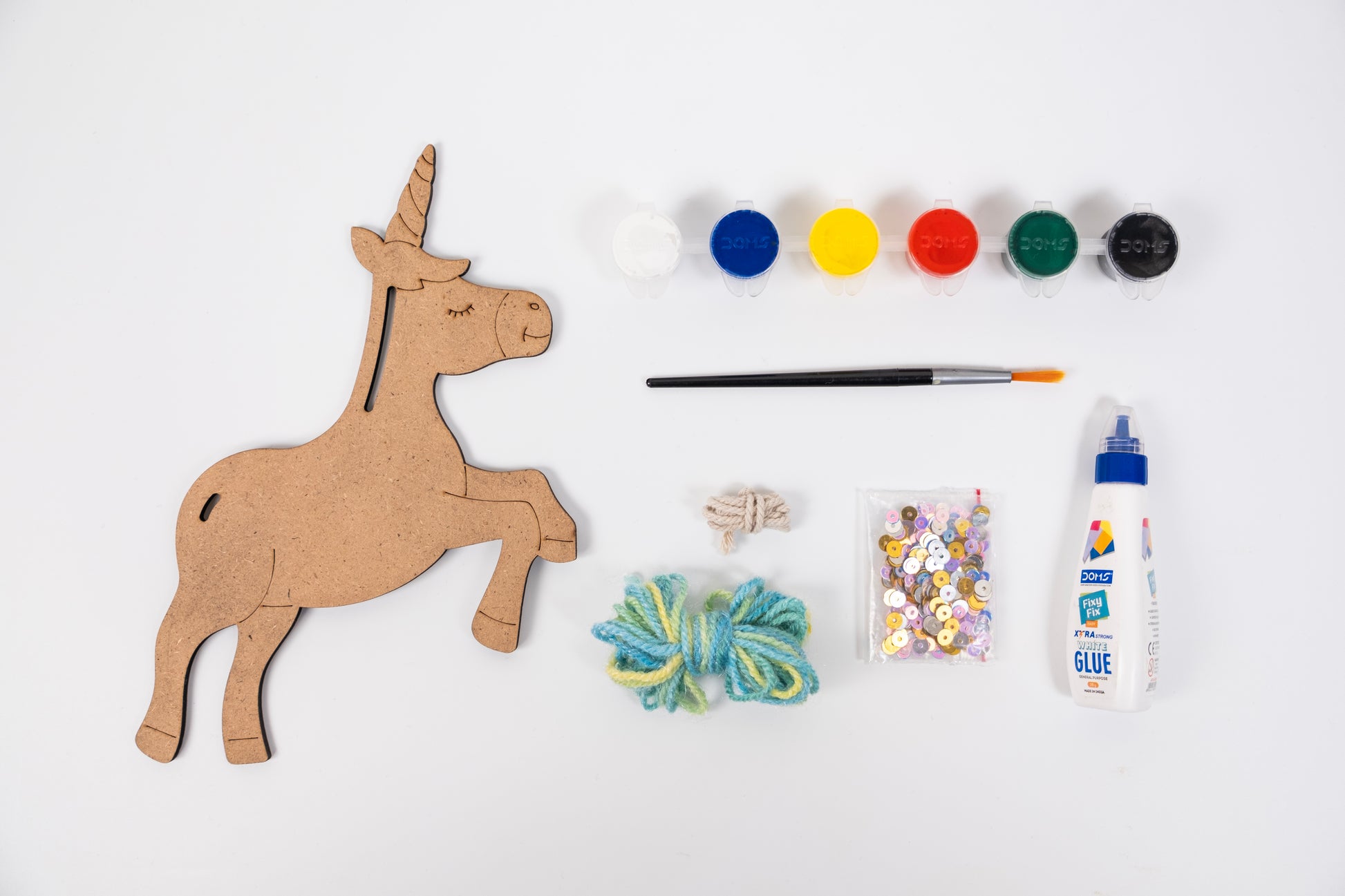 Contents of The Talking Canvas Unicorn Creative Craft Kit with MDF unicorn cutout, yarn, sequins, glue, brush and 6 acrylic paint pots.