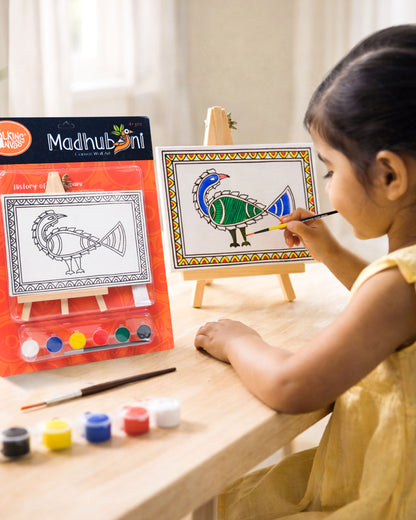 Child painting The Talking Canvas Madhubani Peacock Canvas Wall Art DIY Kit on a wooden easel using the included brush and acrylic paints.