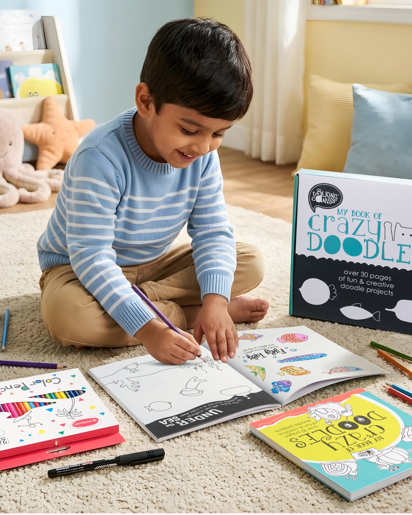 Child enjoying The Talking Canvas My Book of Crazy Doodles kit by drawing in the activity book using colour pencils and marker pen.