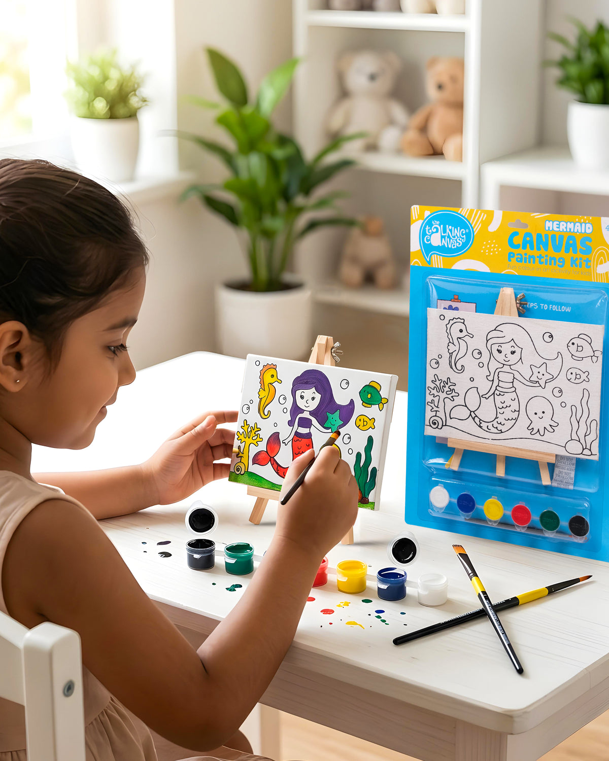 Child painting The Talking Canvas Mermaid Canvas Painting Kit on a wooden easel using the included paints and brush.