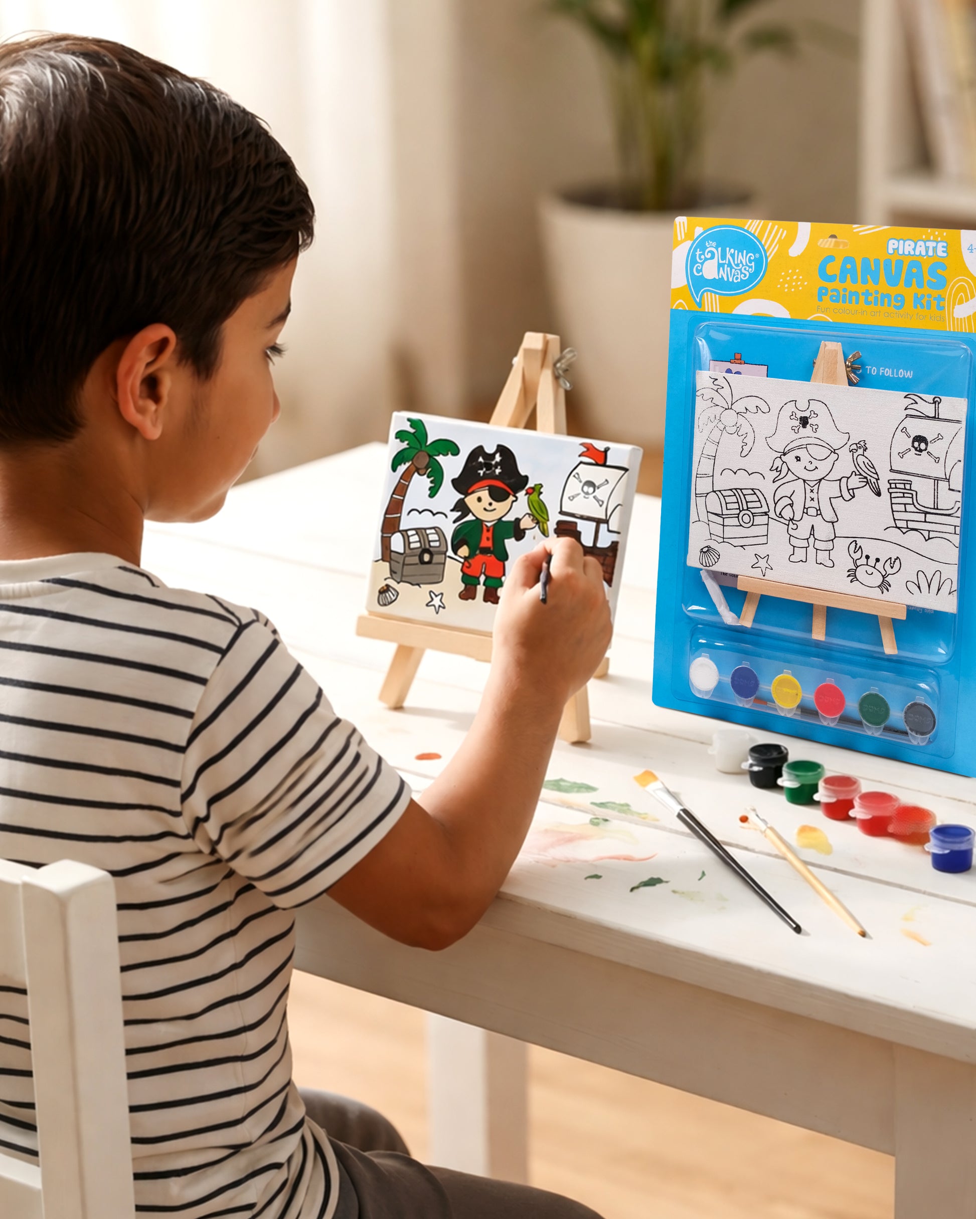 Child painting the Pirate Canvas Painting Kit on a wooden easel using colourful acrylic paints to create a fun pirate adventure scene during a screen-free art activity.