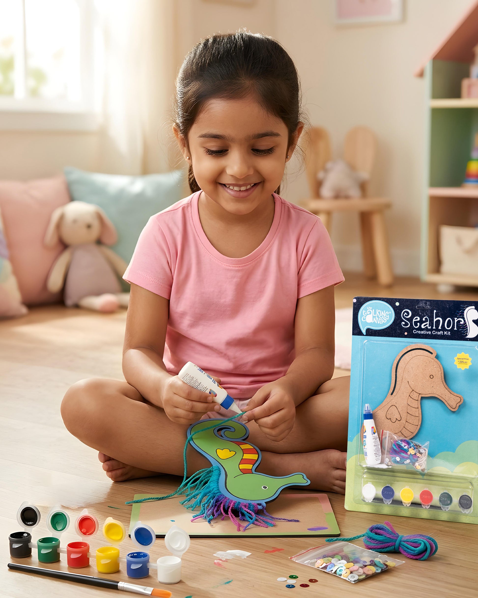 Child creating Creative Craft Kit – Seahorse with painted seahorse, colourful yarn mane, paints, sequins and craft packaging beside artwork.