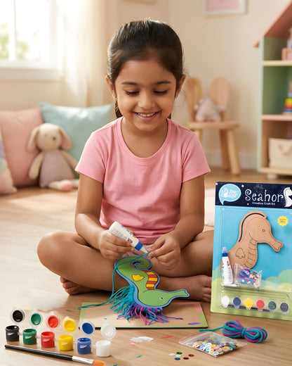 Child creating Creative Craft Kit – Seahorse with painted seahorse, colourful yarn mane, paints, sequins and craft packaging beside artwork.