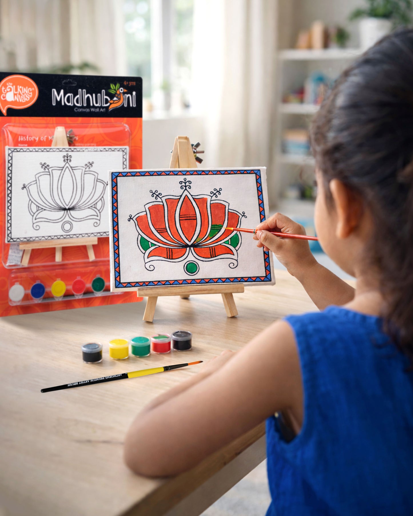 Child painting The Talking Canvas Madhubani Lotus Canvas Wall Art DIY Kit on a wooden easel using the included brush and acrylic paints.